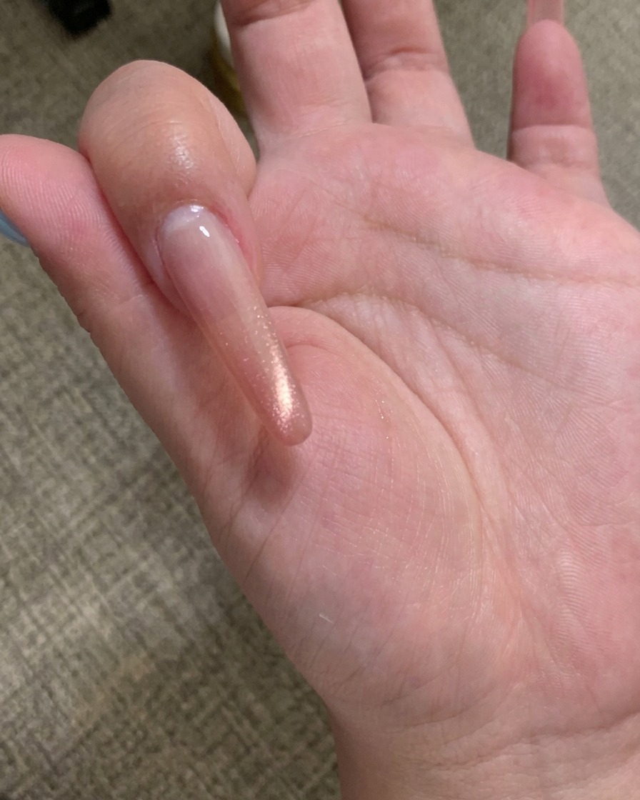 Gros plan dun outil magnétique tenu au-dessus dun ongle avec gel cat eye champagne, montrant les particules se déplaçant en ligne.
