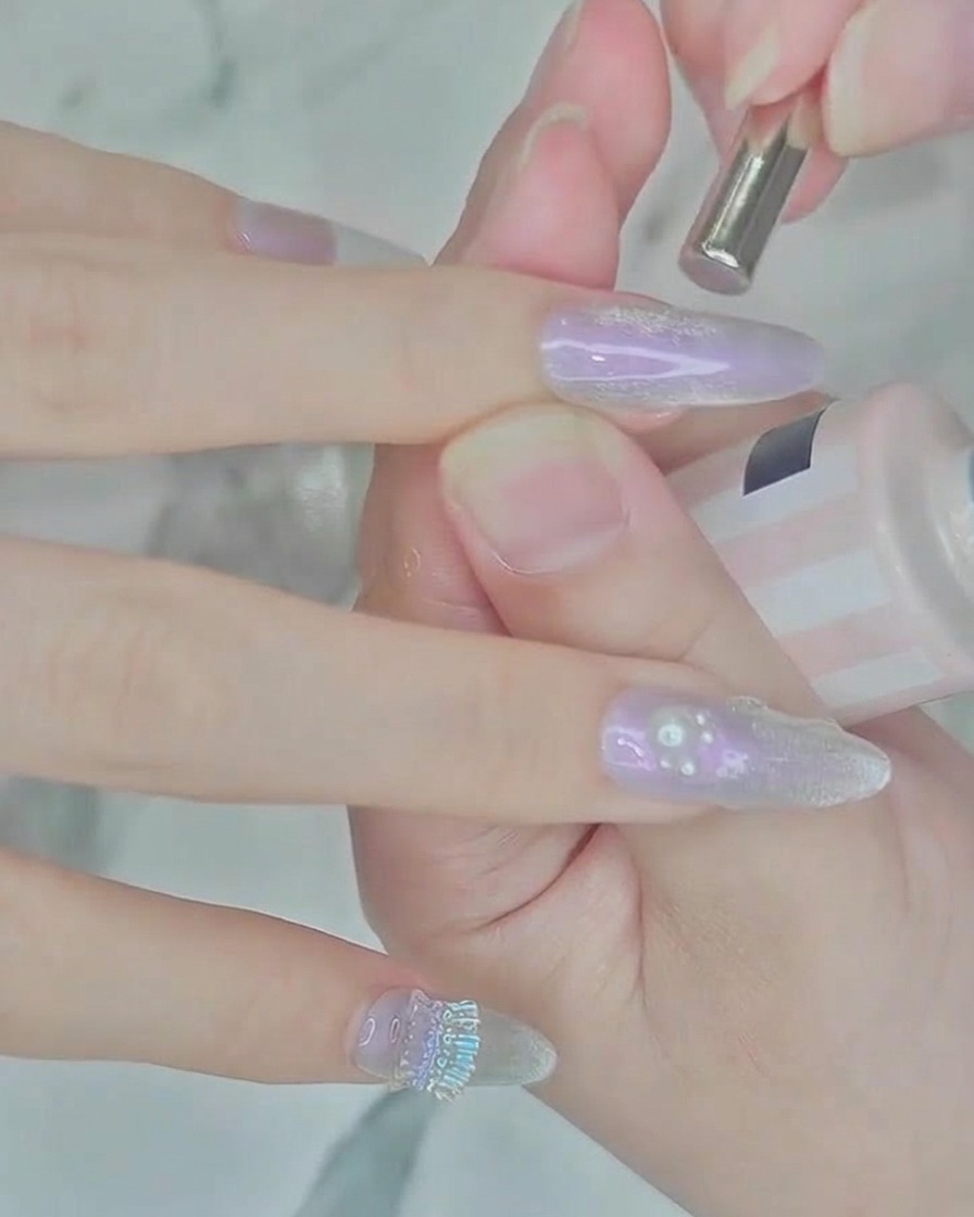 Un petit aimant cylindrique positionné au-dessus dun ongle avec du vernis argenté humide pour créer un effet cat-eye.