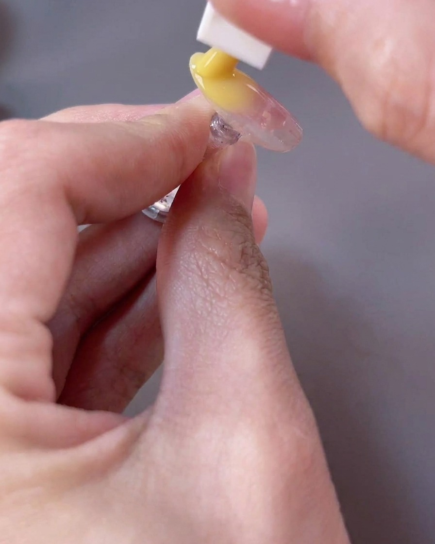 Embout mousse tapotant un gel jaune vif sur le bord libre de longle pour créer un effet dégradé.