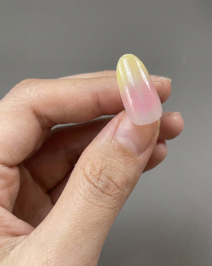 Pinceau appliquant une couche de base transparente et brillante sur un dégradé dongle jaune et rose.