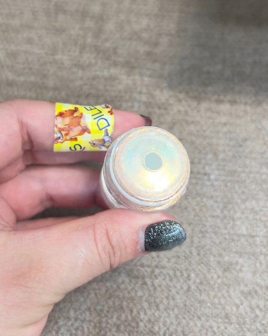 Petit pot de poudre aurora pour ongles révélant un scintillement jaune et bleu.