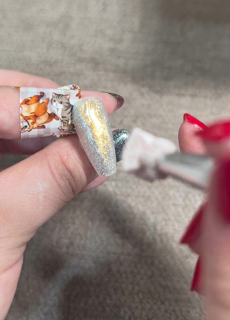 Pinceau estompeur appliquant du gel blush orange sur un ongle scintillant pour créer un dégradé doux.