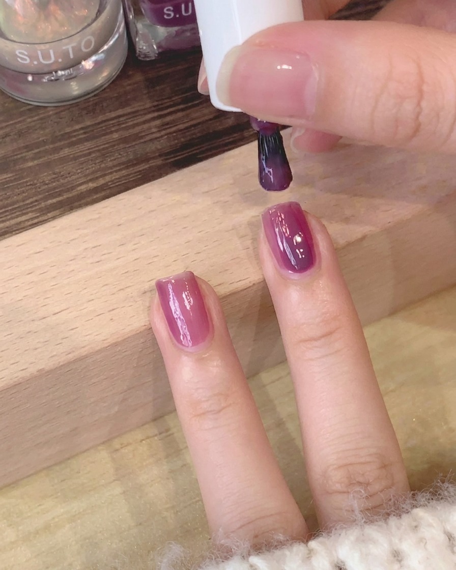 Gros plan dun pinceau lissant la surface du gel violet sur longle.