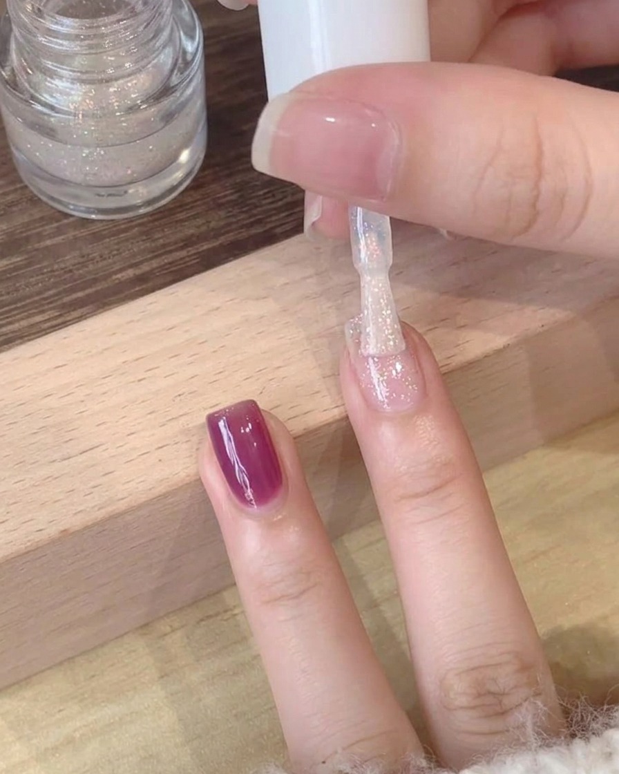 Gros plan dun top coat scintillant et polarisé appliqué sur une base en gel violet profond.