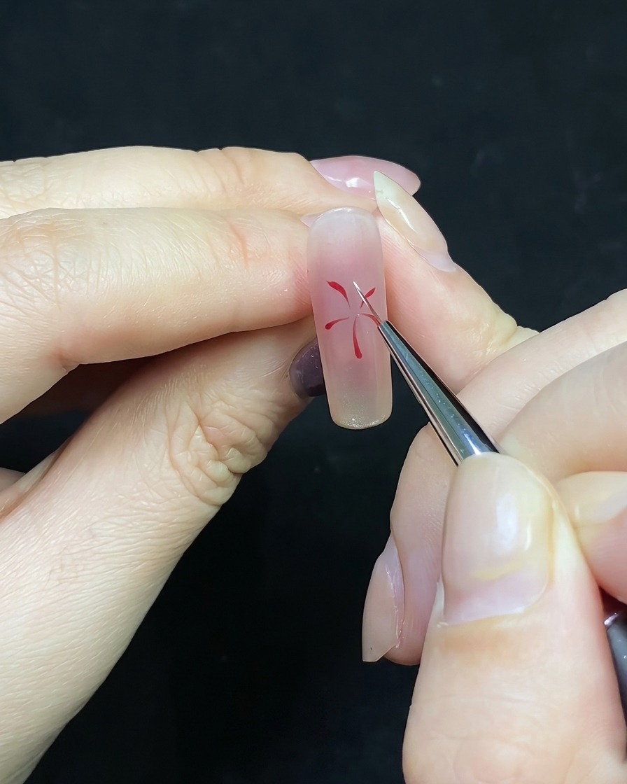 Un pinceau de précision ajoutant des traits blancs entre les lignes rouges existantes du nail art.