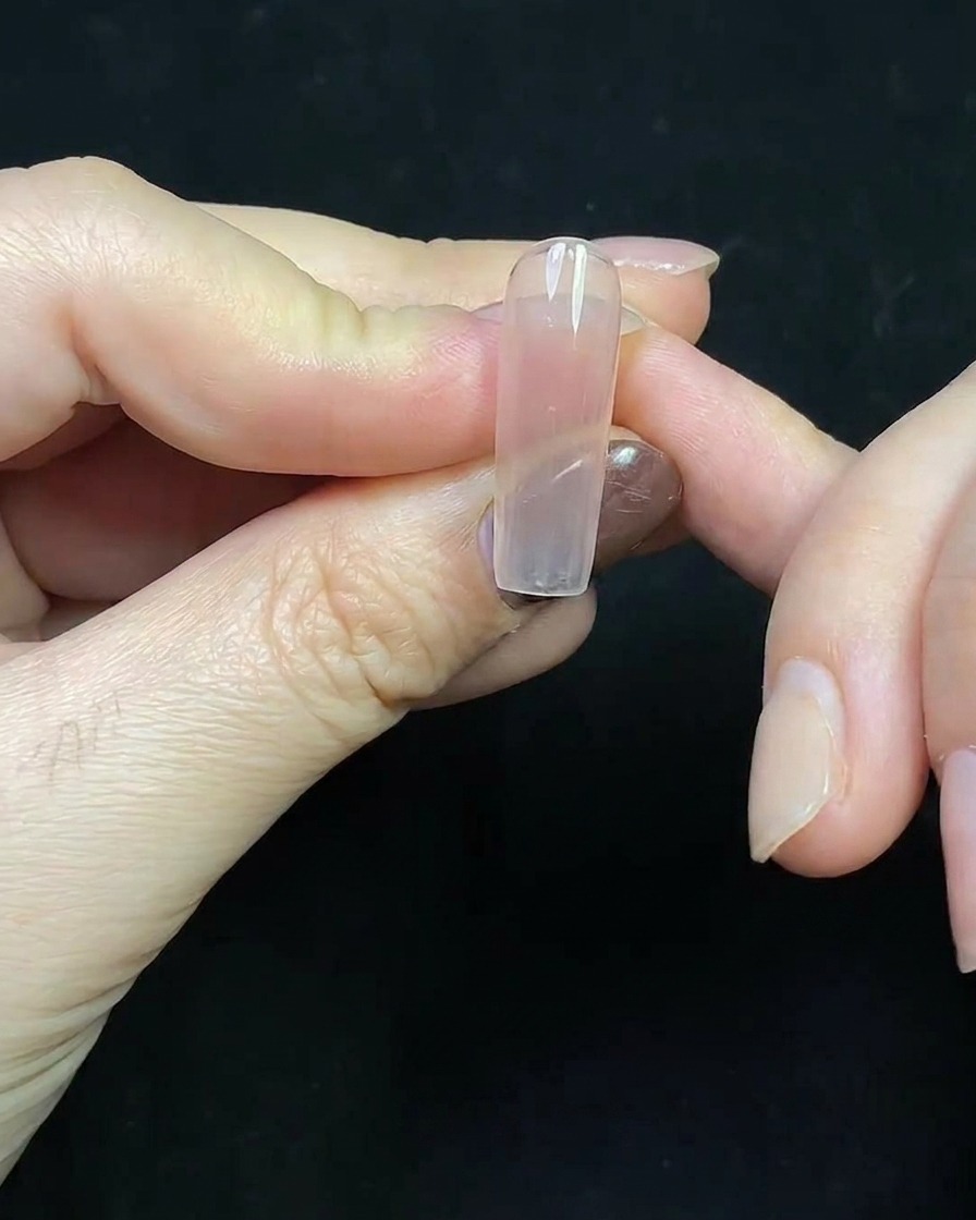 Gros plan dune French manucure en gel rouge profond peinte sur une extension transparente.