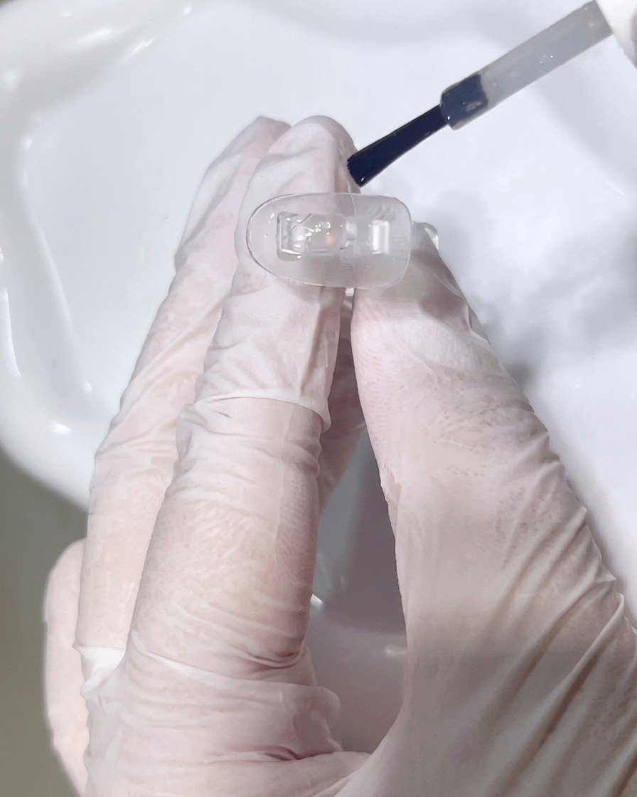 Gros plan sur lapplication dune base transparente sur un ongle.