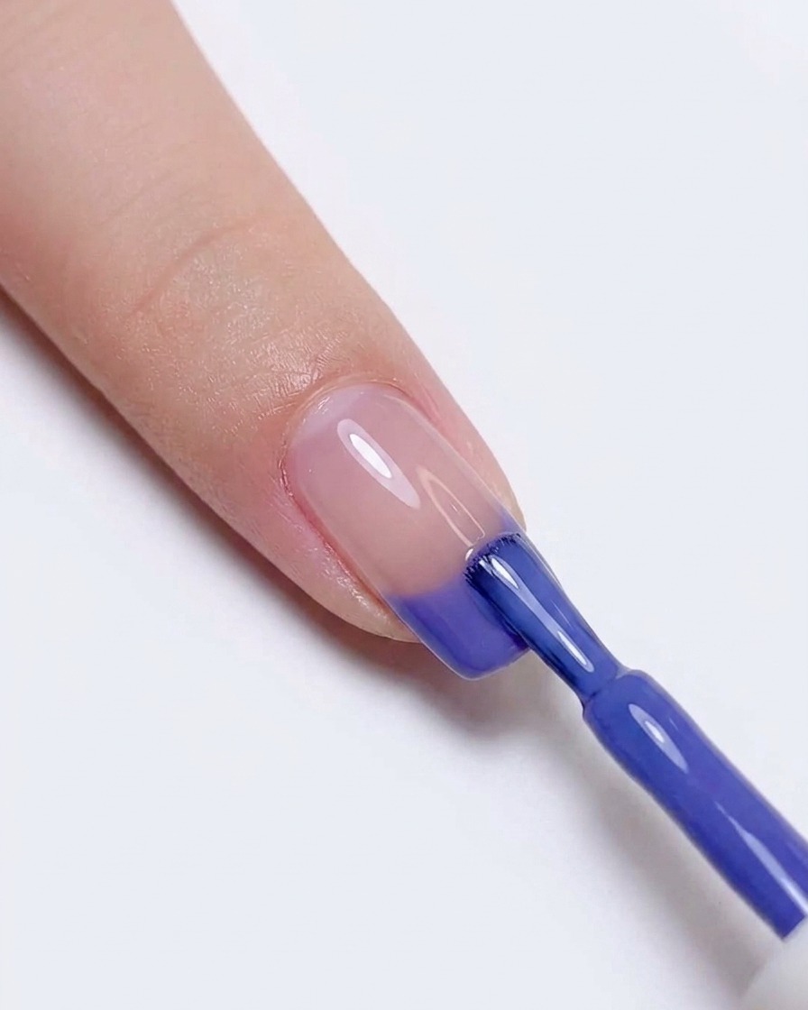 Réapplication de vernis gel bleu et violet sur le bout de longle pour intensifier la transition des couleurs.