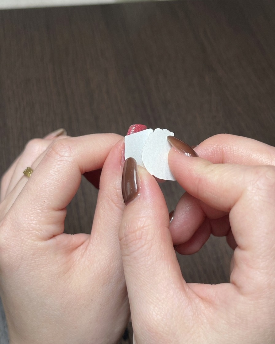Gros plan dune éponge à maquillage tamponnant du gel rouge sur le bord libre dun ongle.