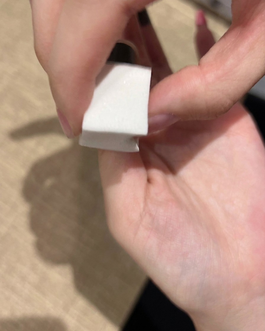 Une éponge à maquillage utilisée pour tapoter délicatement du vernis gel rose sur un ongle afin de construire un dégradé doux et fondu.