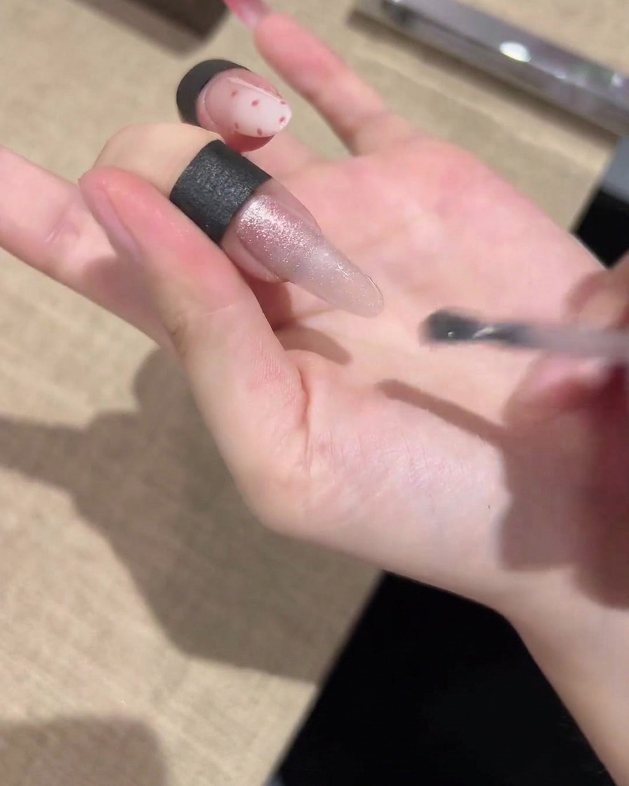 Un pinceau appliquant un vernis gel œil-de-chat scintillant uniformément sur toute la longueur de longle.