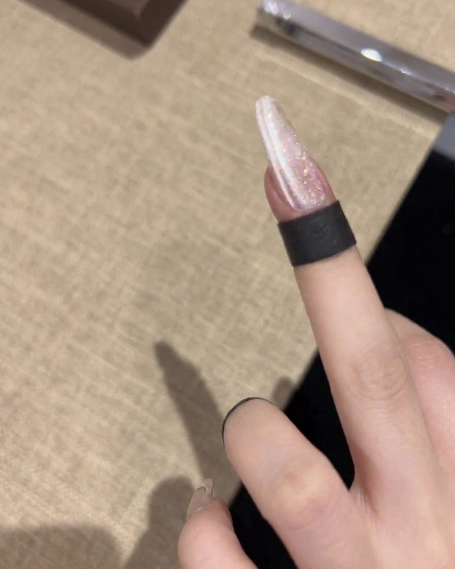 Un outil magnétique tenu horizontalement près de longle, créant une ligne nette et brillante à travers le vernis gel scintillant.