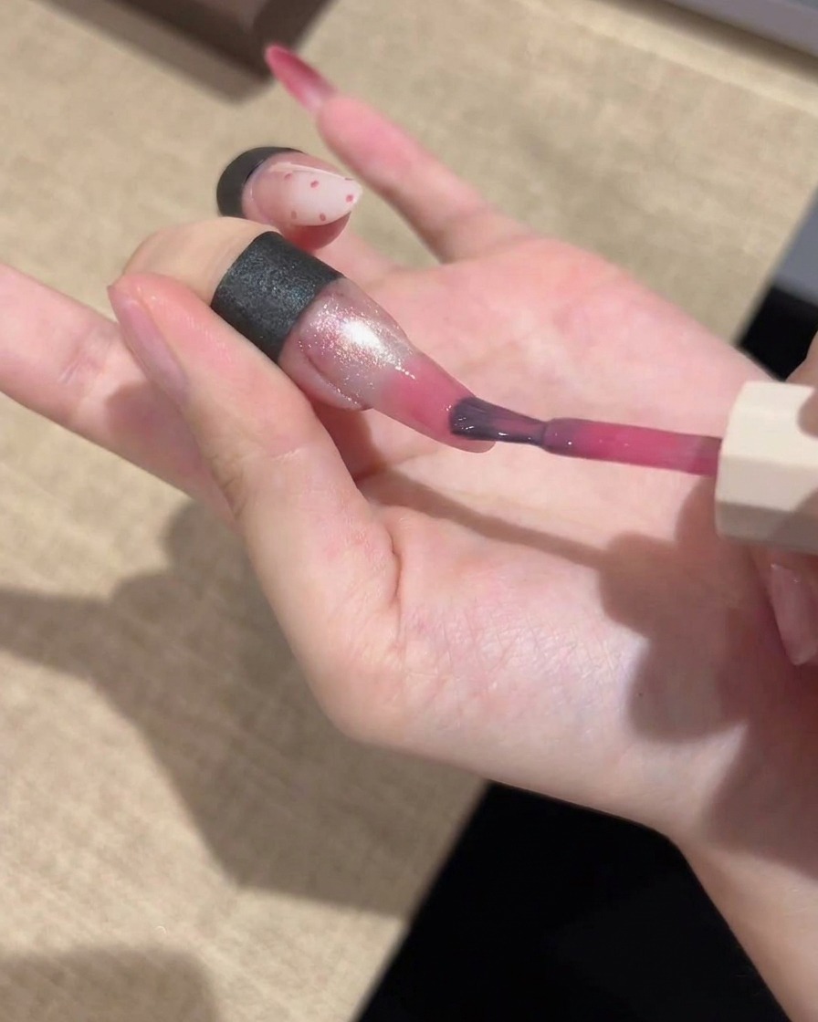 Un pinceau de détail fin appliquant une couleur gel rose vibrante sur le bout dun ongle manucuré, en estompant pour une finition en dégradé.