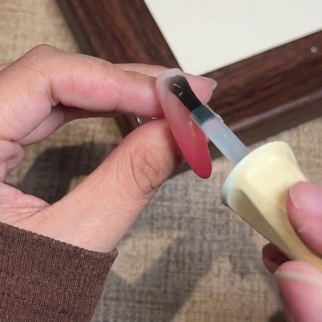 Un pinceau appliquant une couche finale de top coat gel mat transparent sur longle terminé.