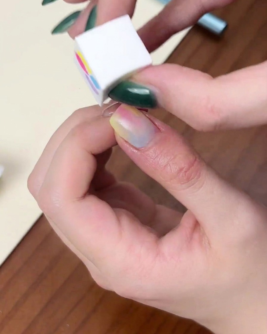 Un ongle placé à lintérieur dune lampe UV/LED rouge en forme de dôme avec la lumière violette allumée.