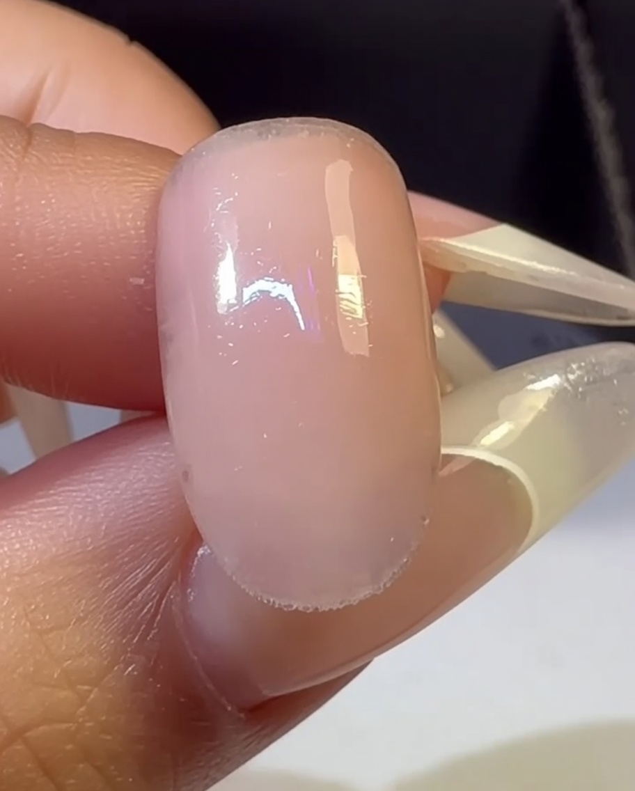 Une main avec un ongle dégradé multicolore placée à lintérieur dune lampe UV pour le processus de catalysation.