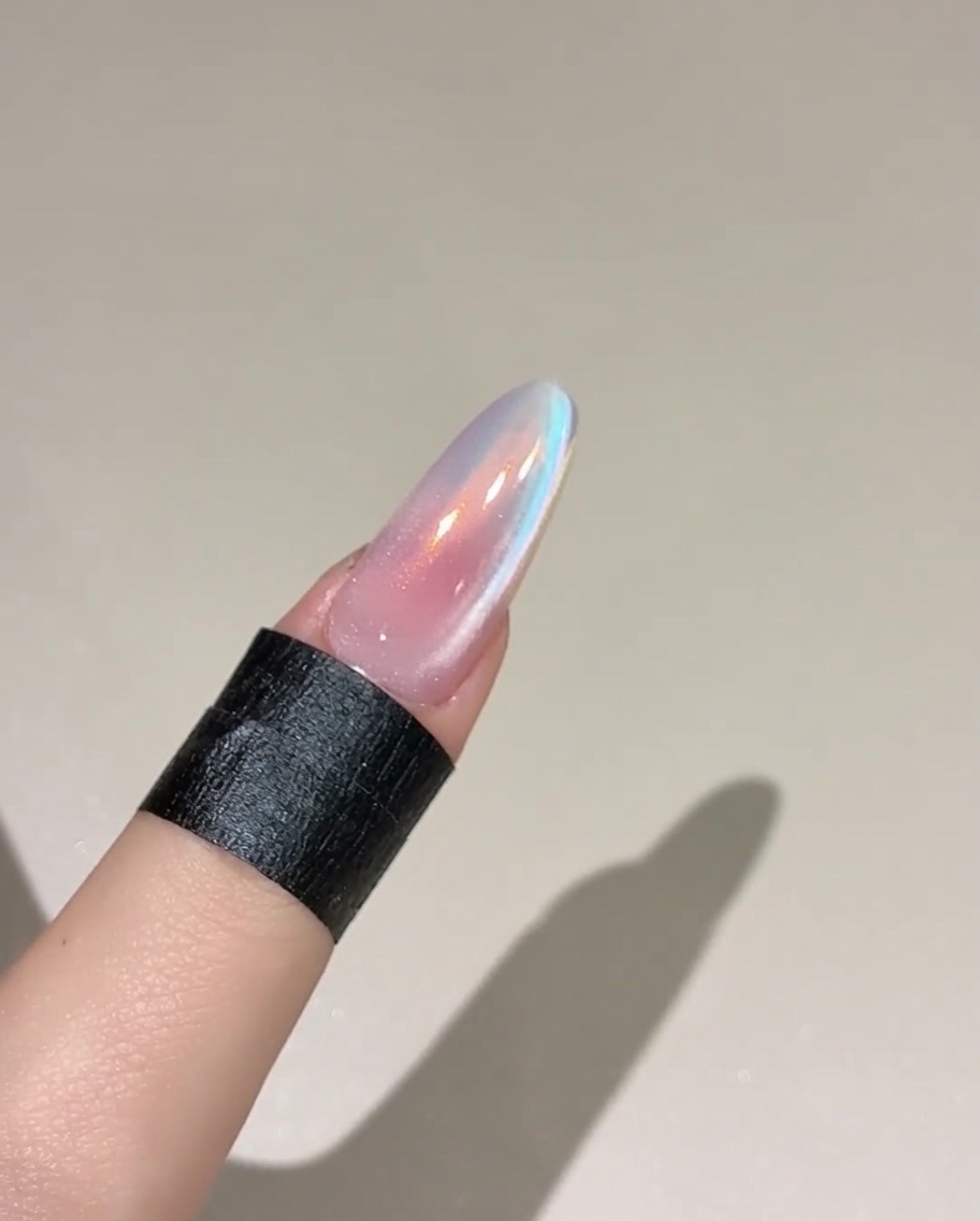 Un pinceau appliquant un top coat sur un ongle rose.