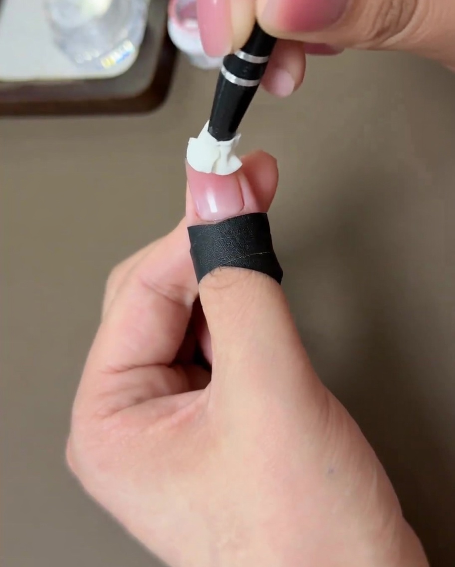 Un ongle avec un effet blush pêche en train de catalyser sous une lampe LED.