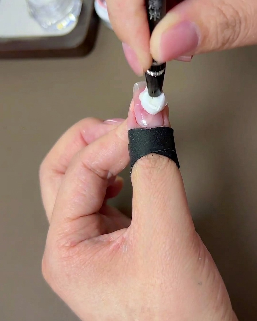 Un pinceau appliquant un deuxième point de gel pêche plus concentré au centre de la couche précédente.