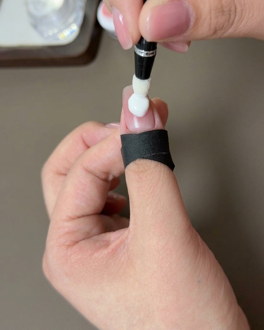 Gros plan sur une main avec un ongle blush pêche en train de catalyser sous une lampe UV professionnelle.