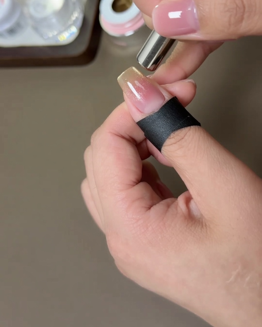 Un aimant cylindrique tenu sur les côtés de longle pour déplacer les particules magnétiques dorées.