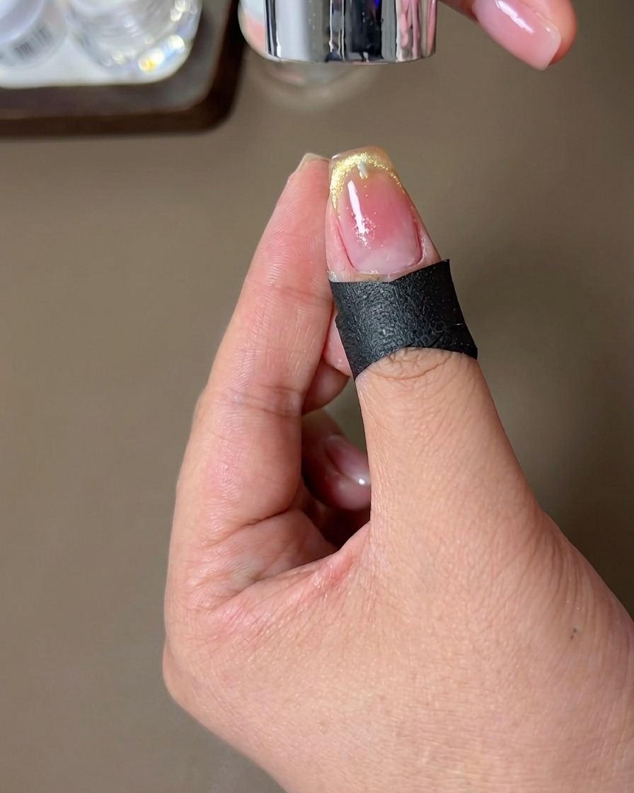 Un ongle avec le design French magnétique fini en train de catalyser sous une lampe à ongles.
