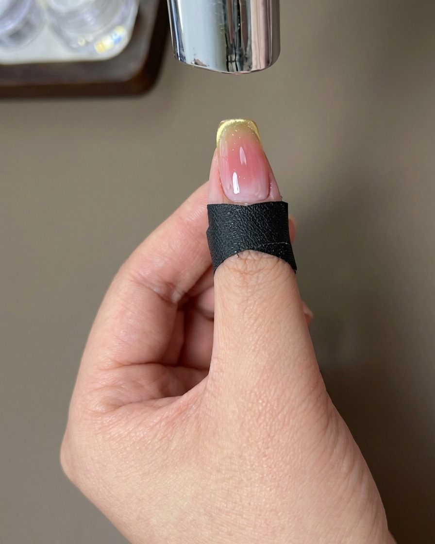Un ongle avec un design dégradé fini positionné sous une lampe UV pour catalyser.