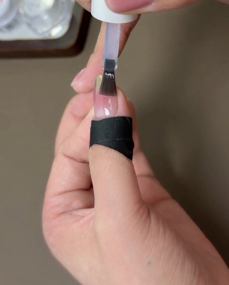 Un ongle fini avec un top coat de renforcement, en train de catalyser sous une lampe UV.
