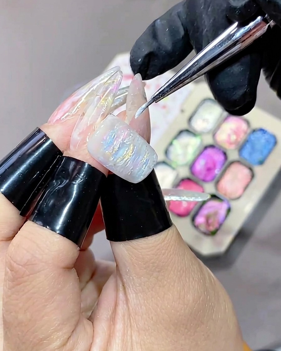 Un pinceau fin appliquant un gel blanc enlumineur sur la surface texturée dune manucure en gel.