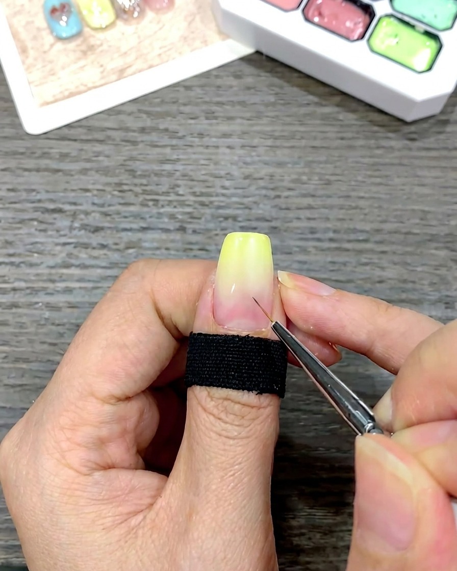 Un pinceau fin détail appliquant de petits points guides blancs au centre dun ongle avec un dégradé jaune.