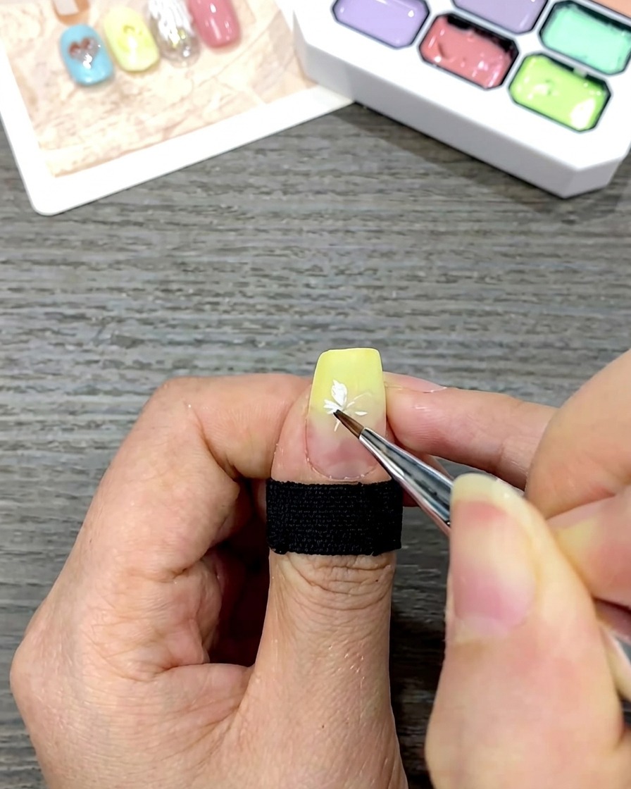 Gros plan dun ongle montrant une marguerite blanche terminée sur une base dégradée jaune.