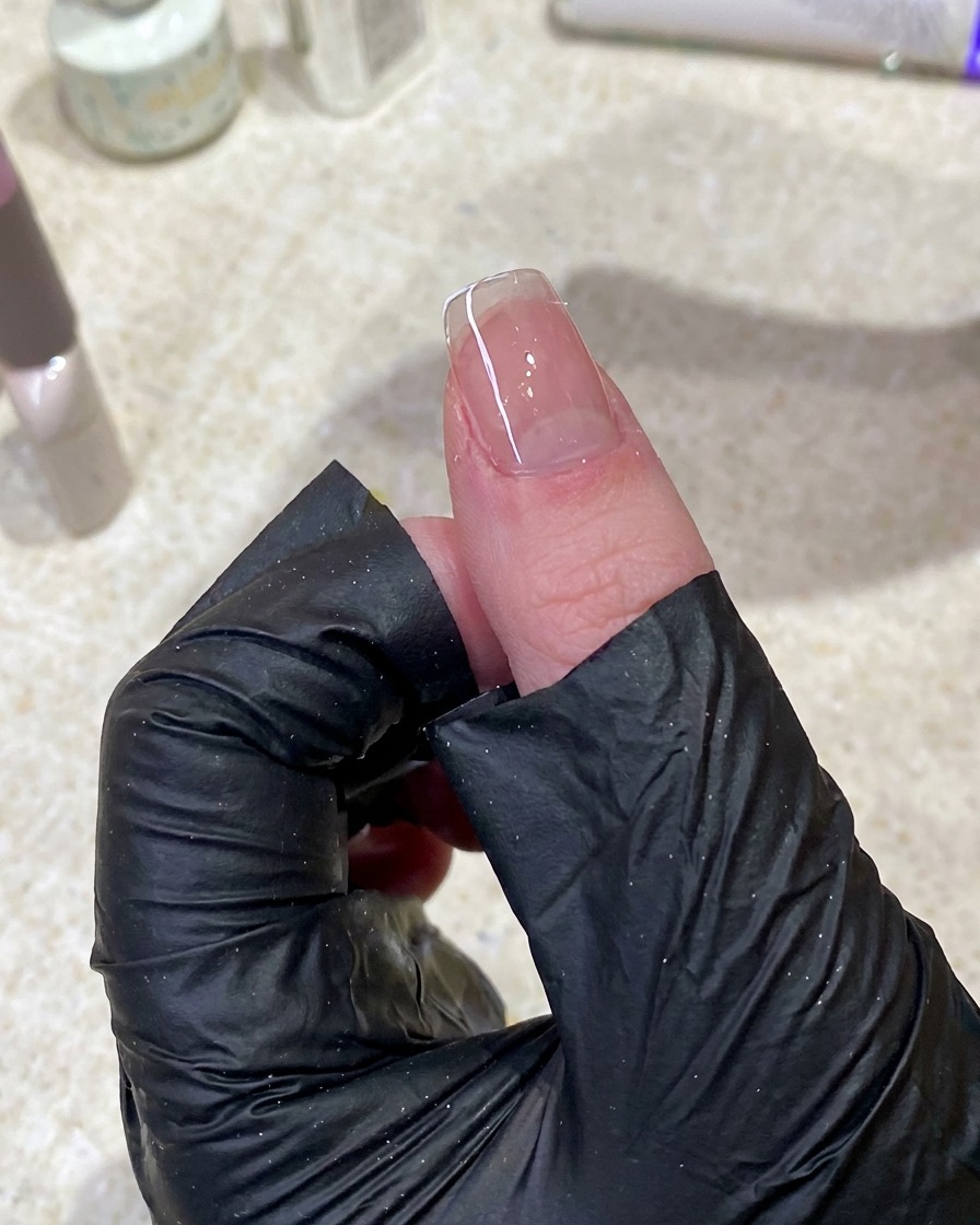 Gros plan dune main utilisant un coton non pelucheux pour nettoyer la surface dun ongle.
