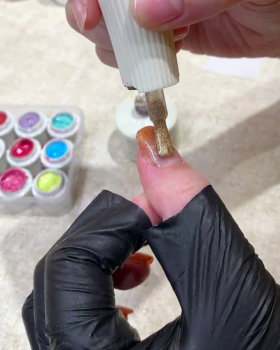 Un aimant maintenu au-dessus dun ongle en gel non catalysé pour déplacer les particules magnétiques et créer une ligne lumineuse.