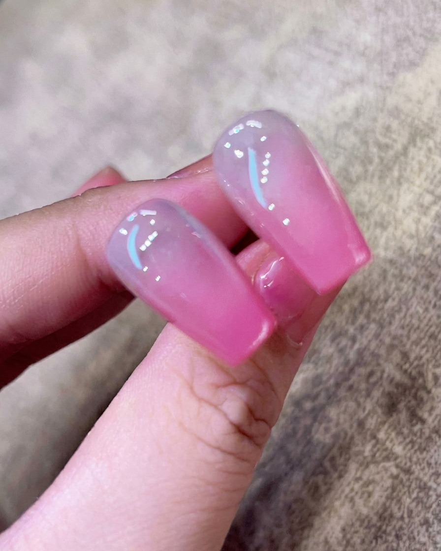 Gros plan dune base transparente appliquée au pinceau sur un ongle naturel propre.