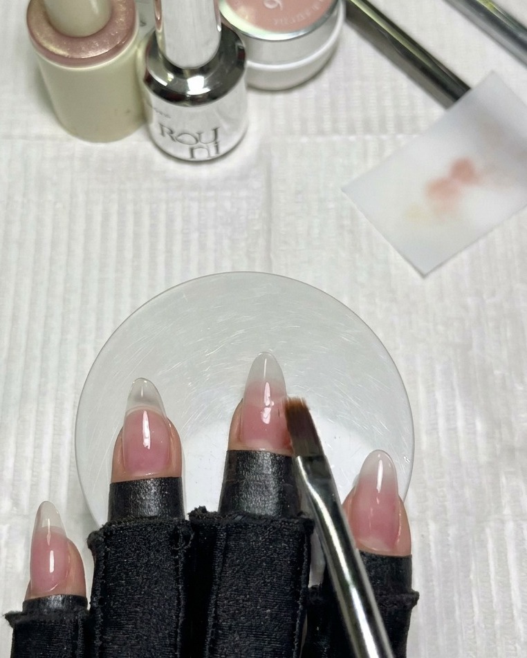Un pinceau dégradé plat propre estompe doucement le bord du vernis blanc sur longle adjacent.