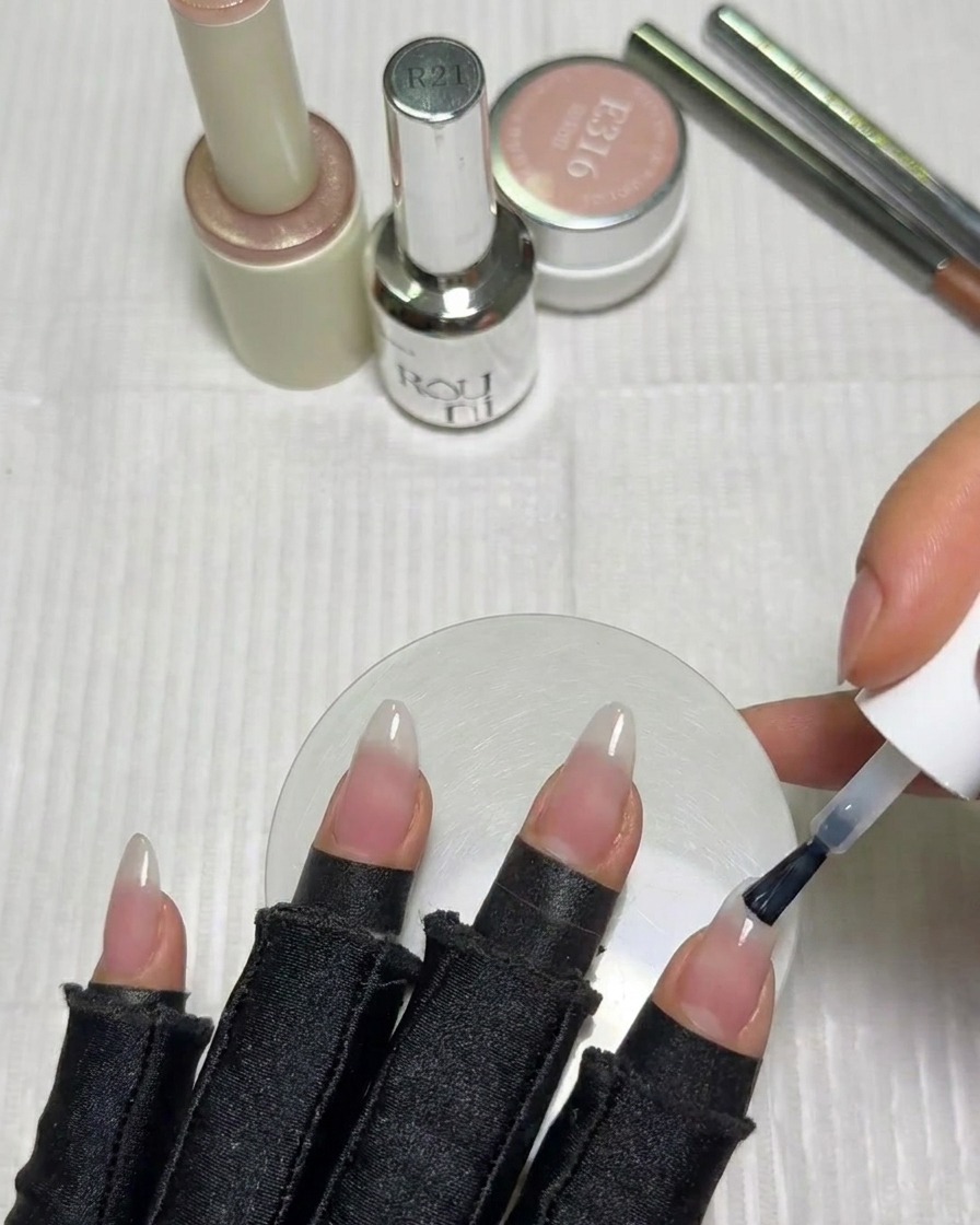 Un pinceau à ongle appliquant une petite quantité de vernis gel blanc sur le bord libre de longle.