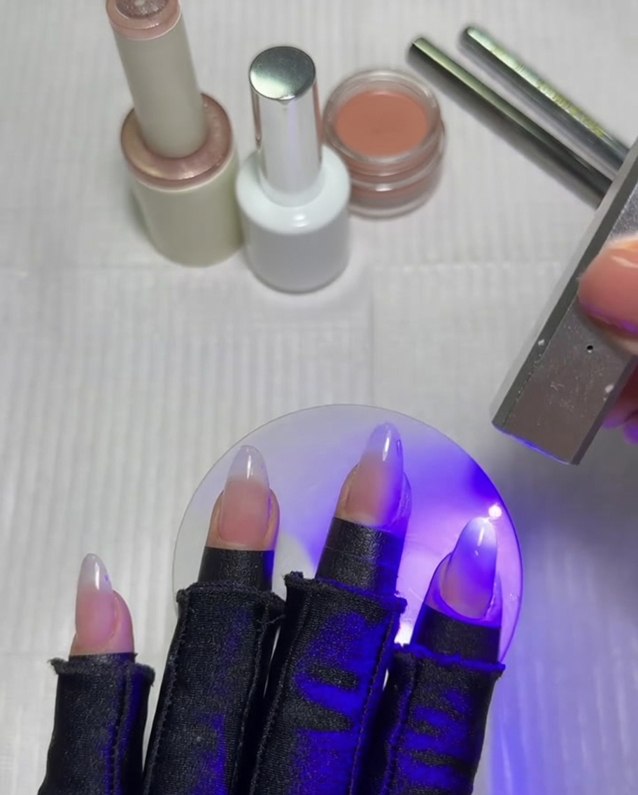 Un pinceau dégradé plat estompant une couche de gel blanc sur un ongle.