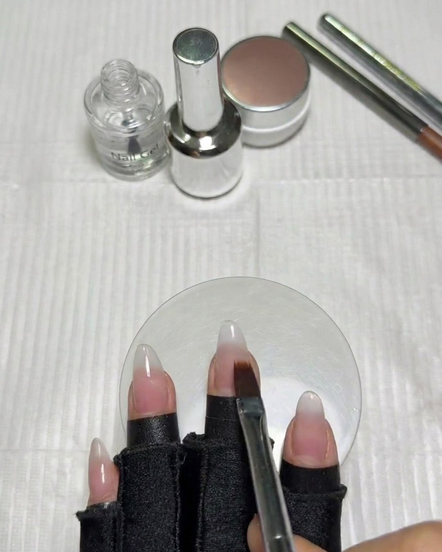 Une main avec des ongles en dégradé placée sous une lampe UV/LED pour la catalysation.