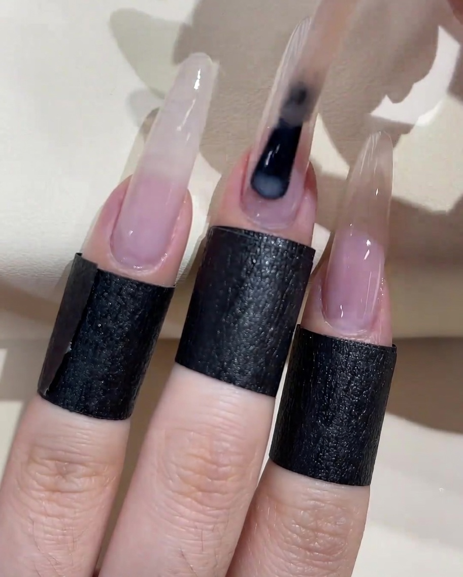 Un pinceau appliquant une seconde couche de vernis gel pêche laiteux sur la surface de longle.