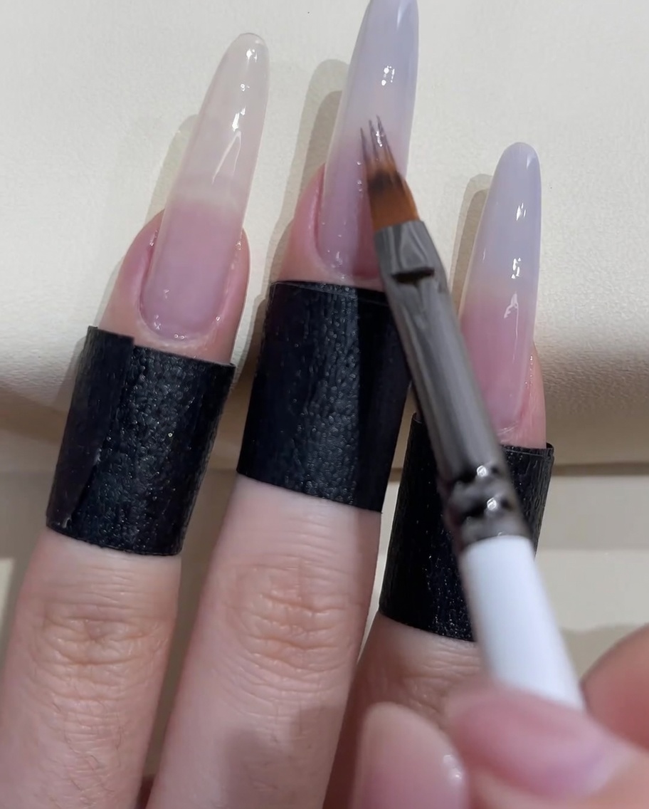 Un pinceau spécial ombré estompant le vernis bleu-gris vers le bas de longle.