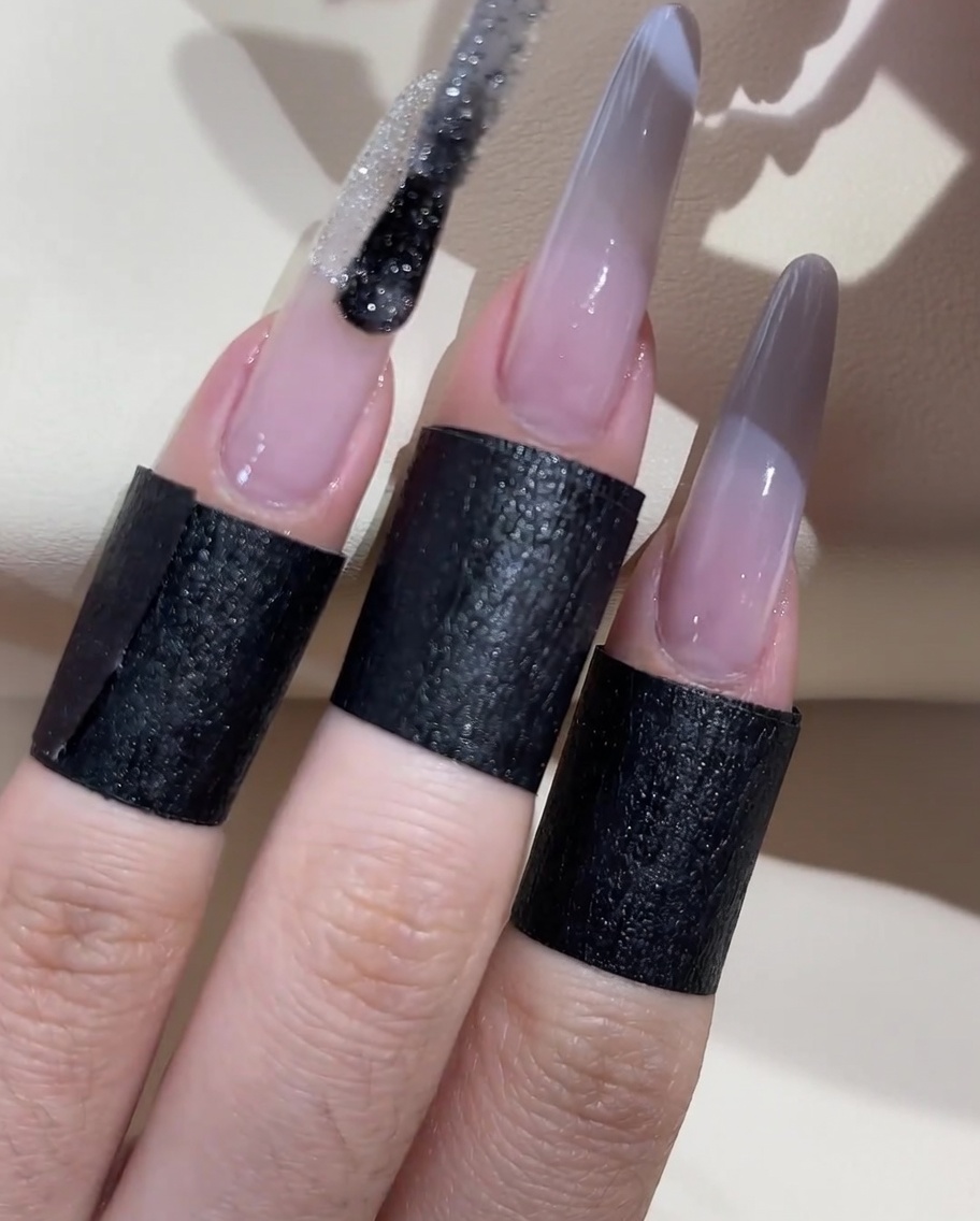 Un pinceau appliquant une ligne de vernis à paillettes argentées au milieu de la transition ombré.