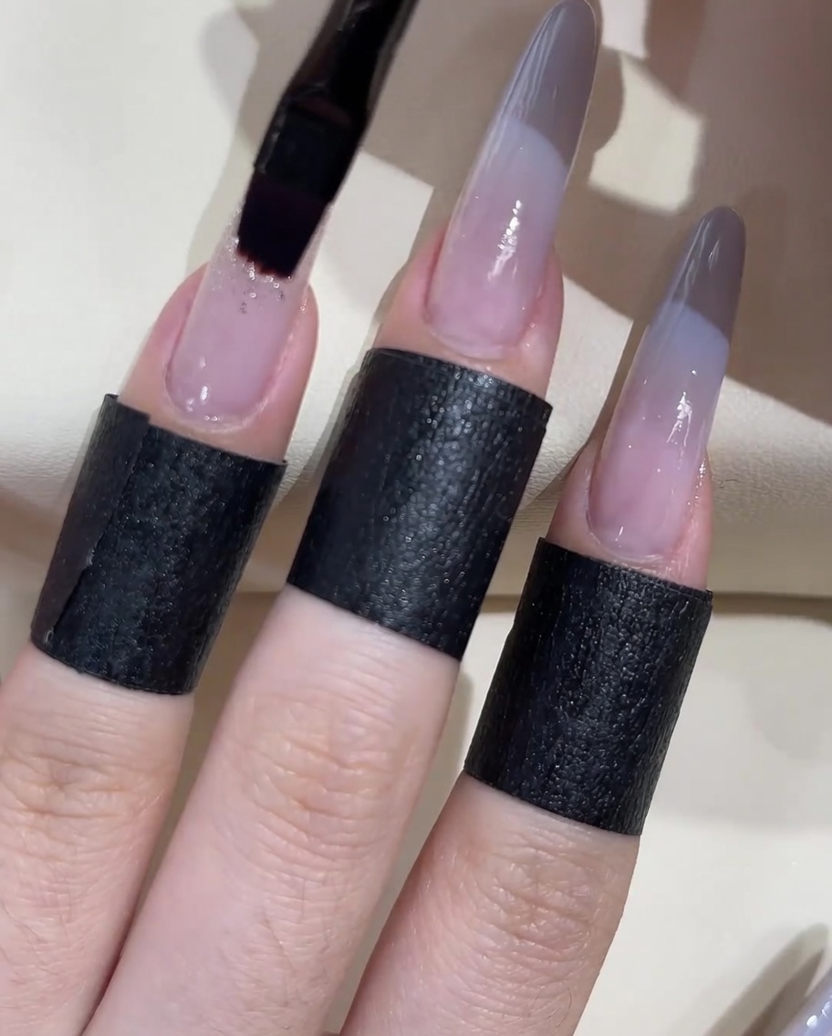Un pinceau gel plat appliquant une goutte de gel adhésif transparent épais sur la surface de longle.