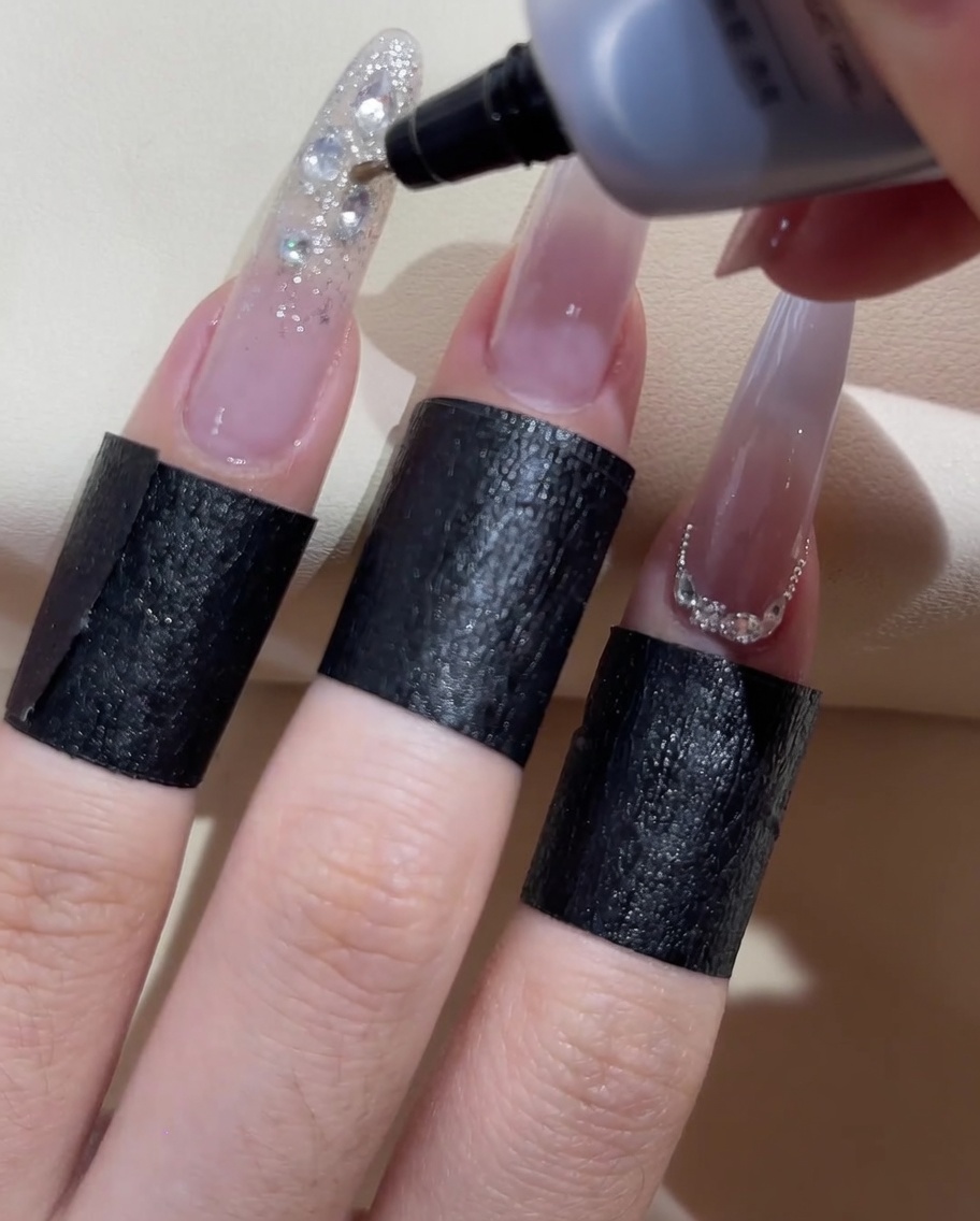Un flacon à embout fin appliquant un gel détanchéité transparent autour des bords des strass décoratifs.