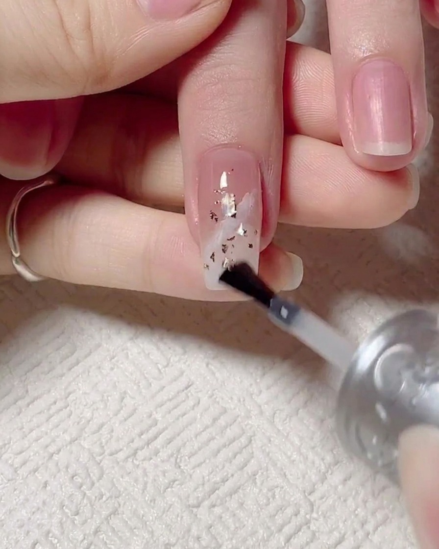 Application dun top coat brillant sur longle décoré, puis catalyse sous lampe UV.