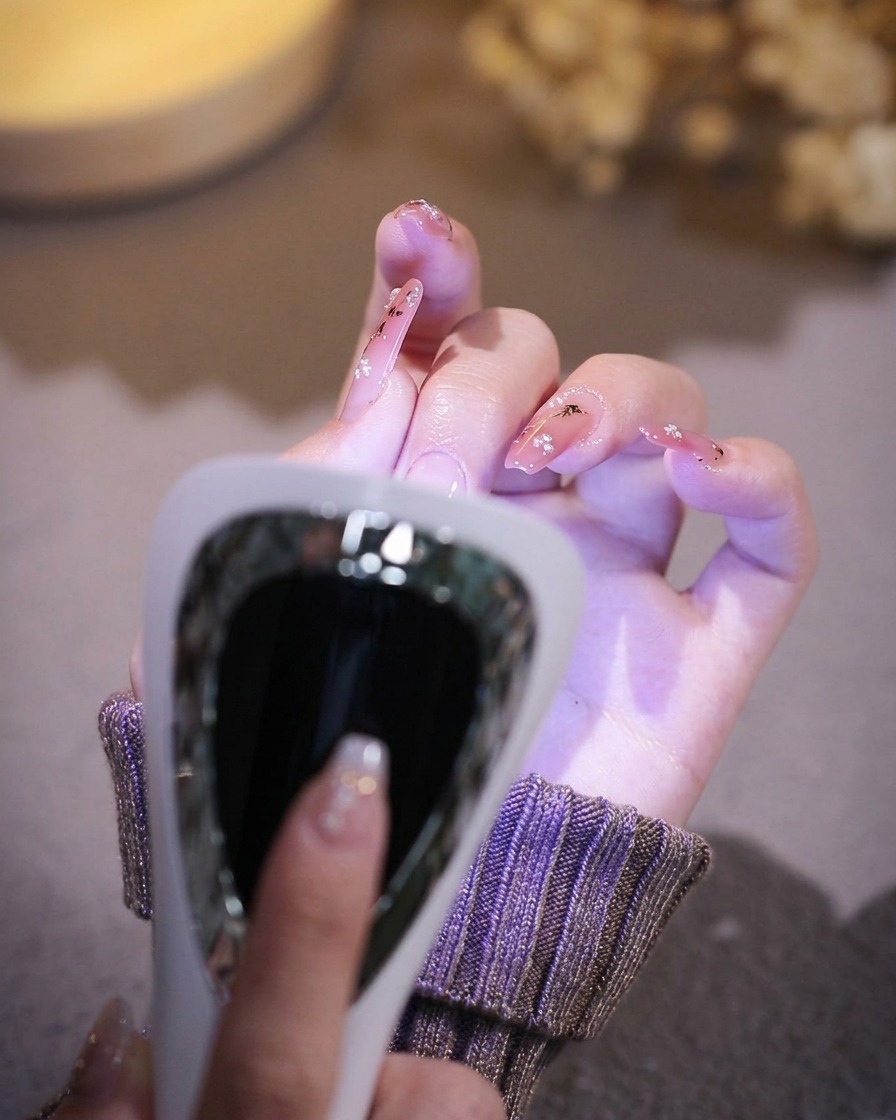Une main posée dans une lampe à ongles UV/LED professionnelle avec la lumière activée.
