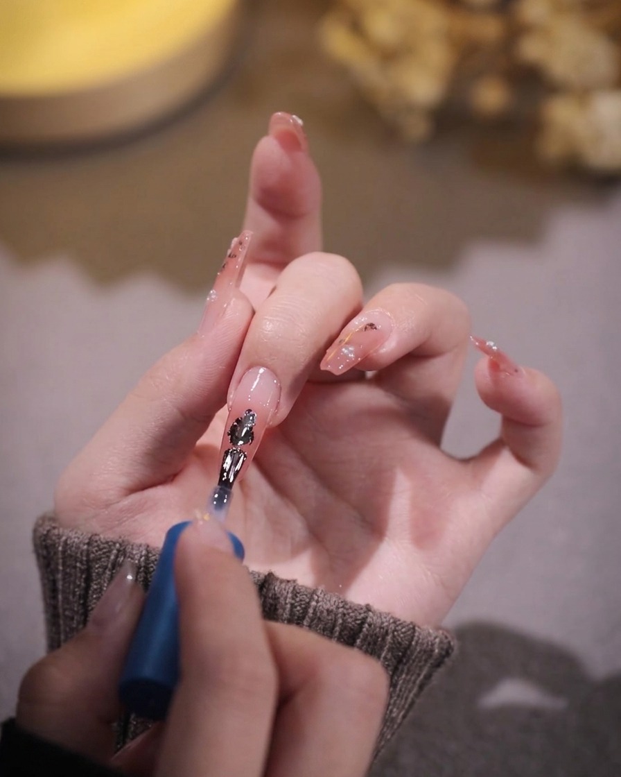 Un pinceau appliquant une seconde couche fine de gel rose transparent sur la première couche catalysée.