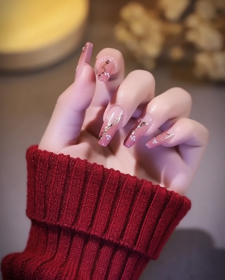 Ongles avec accents de feuille dor catalysant sous une lampe à ongles UV/LED.