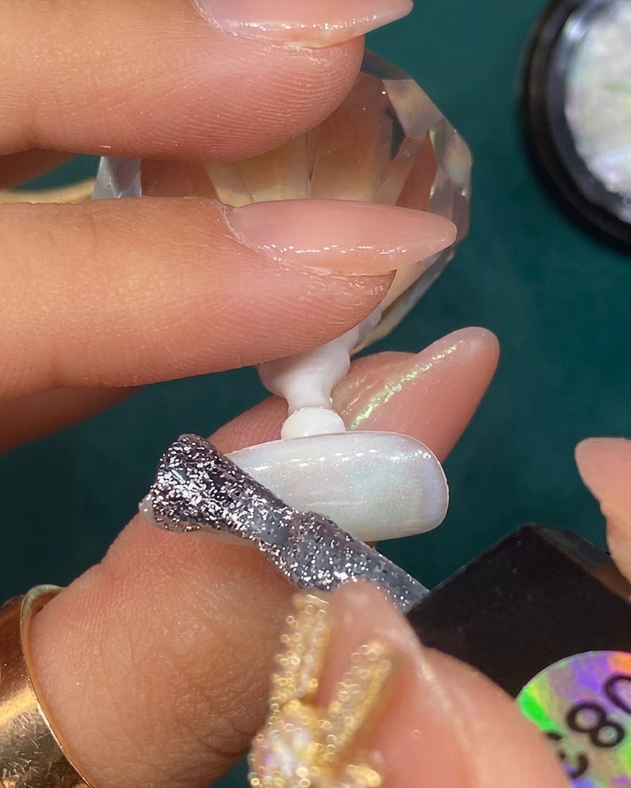 Du gel à paillettes argentées est estompé en dégradé sur le bout dun ongle blanc translucide.
