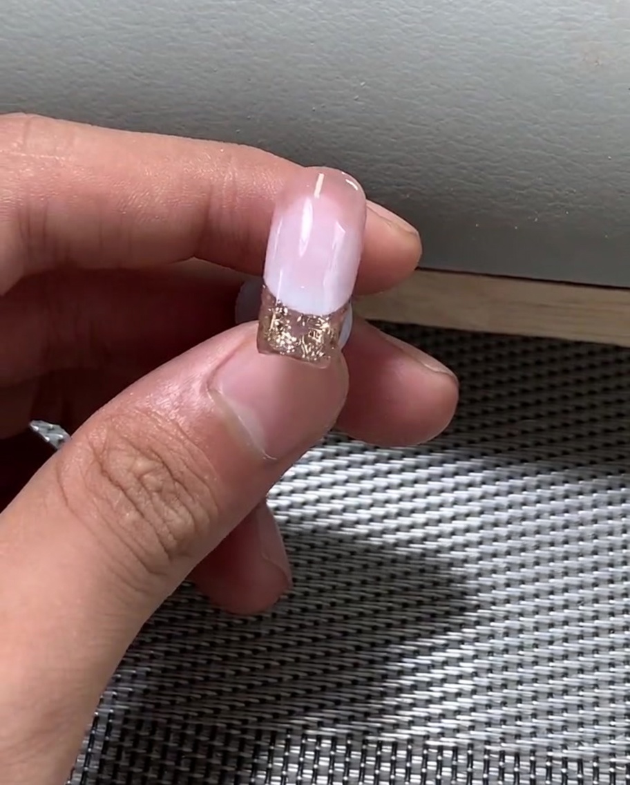 Une main positionnée sous une lampe UV professionnelle pour catalyser le vernis gel.