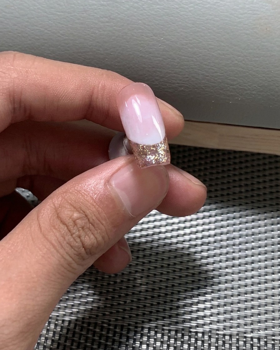 Gros plan de vernis à paillettes fines appliqué sur le bord libre de longle.